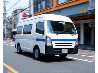荷物を積み込んだ軽バンが街中を走る